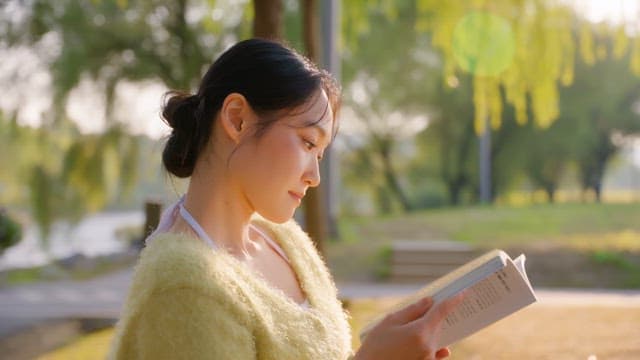 Woman reading a book in a sunny park