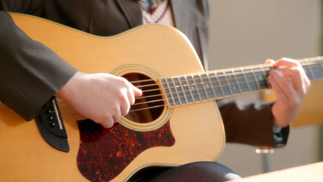 Student playing an acoustic guitar