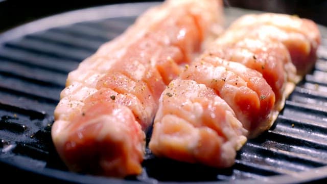 Seasoned pork grilling on a hot pan