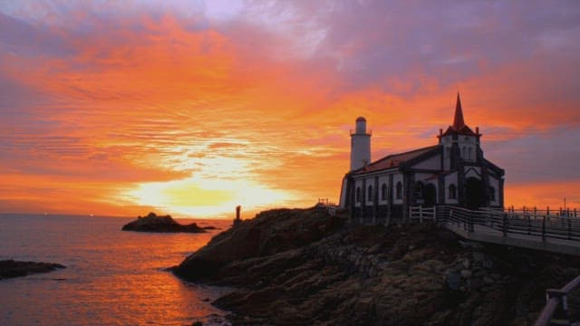 Sunset coloring the seaside sky with a quiet cathedral setting