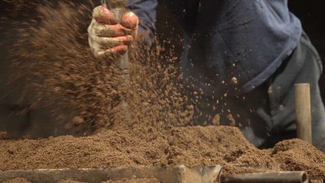 Worker compacting soil with tool