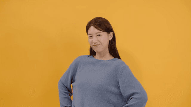 Woman posing confidently in front of yellow background