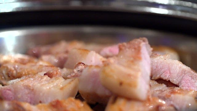 Grilled pork belly sizzling in a pan