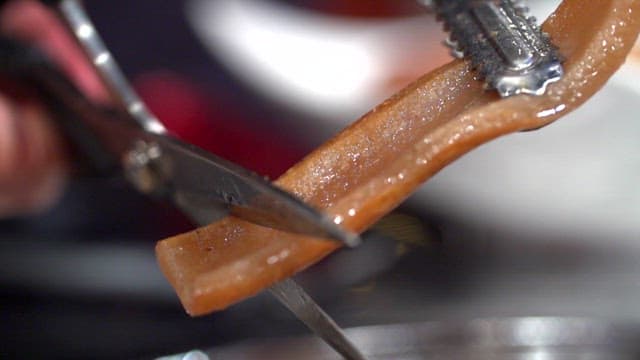 Cooked pork rinds cutting with scissors