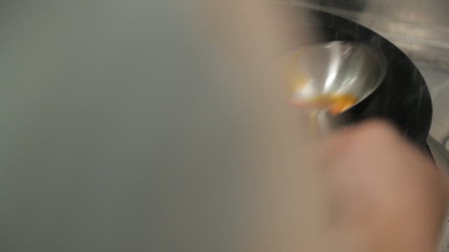 Pouring chili oil with a ladle into a hot wok