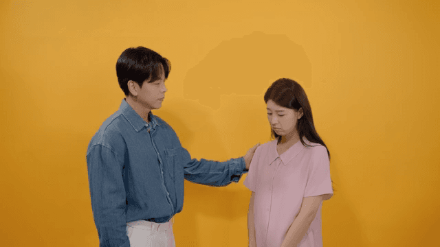 Man comforting a sad woman against a yellow background