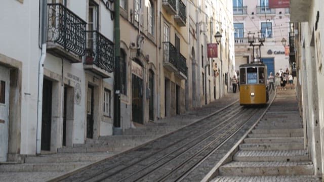 Yellow Tram Moving Downhill in a European City