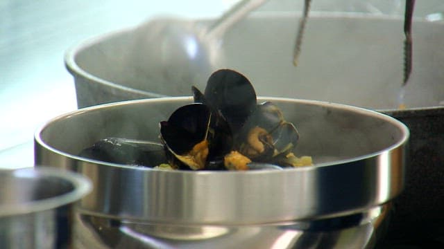 Plating the deliciously cooked mussel soup in a stainless steel bowl