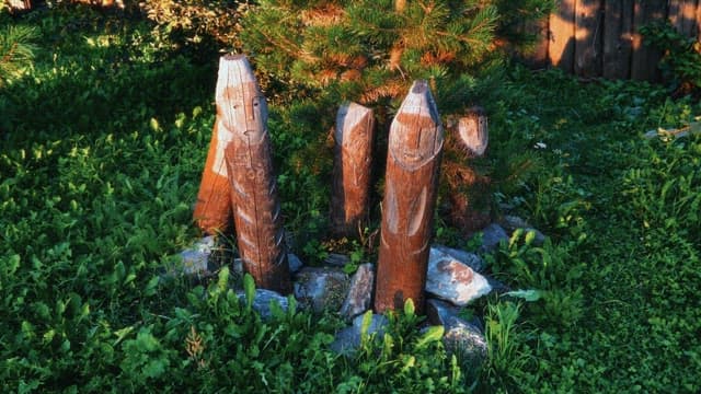 Wooden sculptures in a grassy garden under sunlight