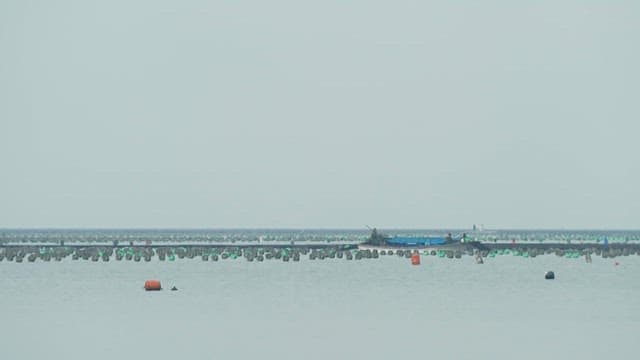 Boat passing by peaceful fish farms on a cloudy day