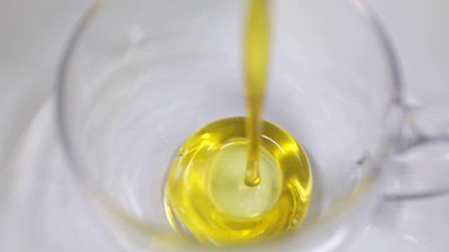 Yellow Omega Oil Pouring into a Transparent Bowl