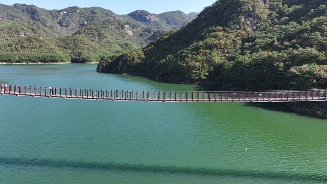 View of a Suspension Bridge with Scenic Lake and Mountain