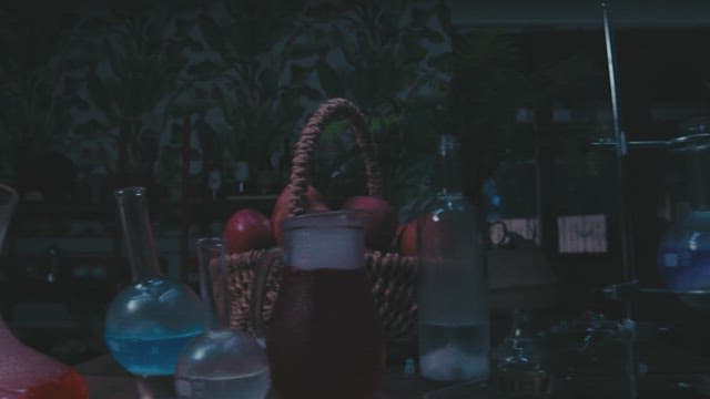 Man examining apple with magnifying glass in a dimly lit lab