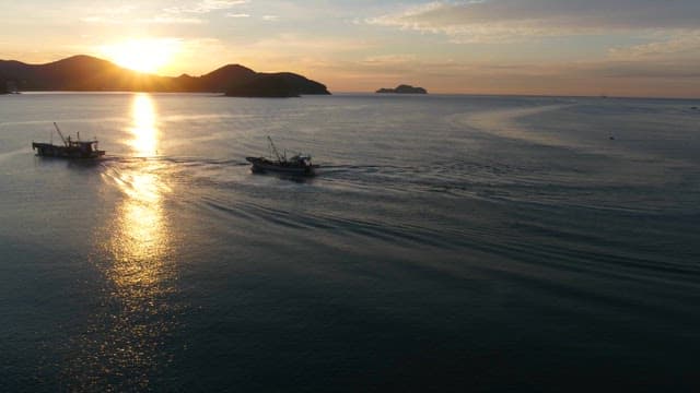 Fishing Boats at Sunset Near Coastal Hills