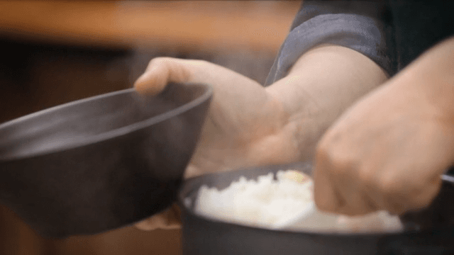 Steaming rice being served into a bowl