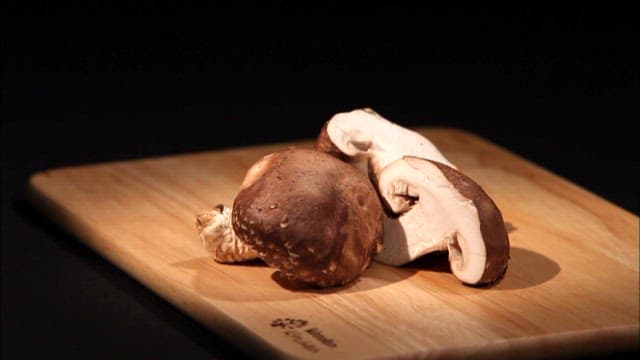 Mushrooms on a wooden cutting board in a dark room under lighting