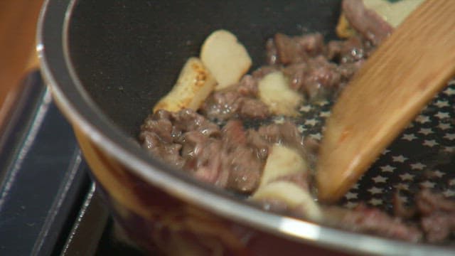Cooking beef with sliced garlic in a frying pan