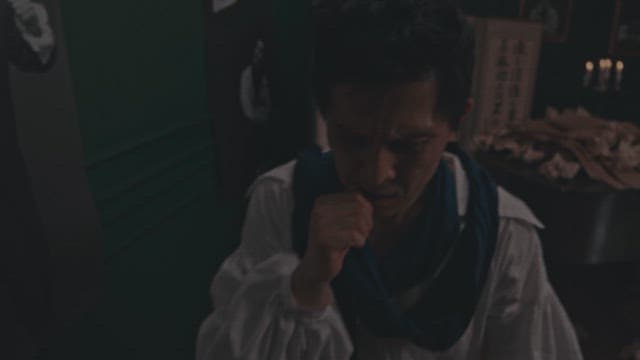 Man suffering in a dark room with a table set up for ancestral rites