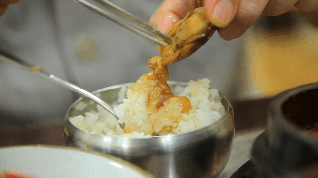 Soy sauce marinated crab being placed on rice