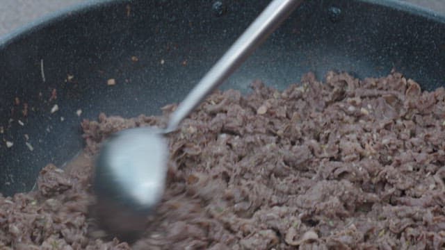 Cooking beef bulgogi with a spatula in a frying pan