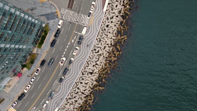 Vehicles moving on a beach road with a breakwater