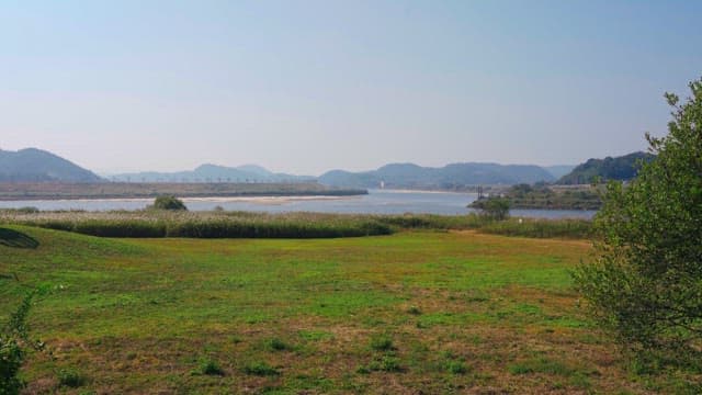 River surrounded by mountains and fields under a clear sky