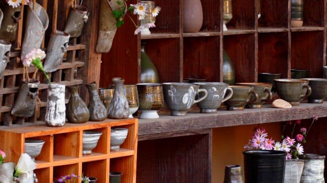 Wooden shelf displaying clay pottery cups and vases