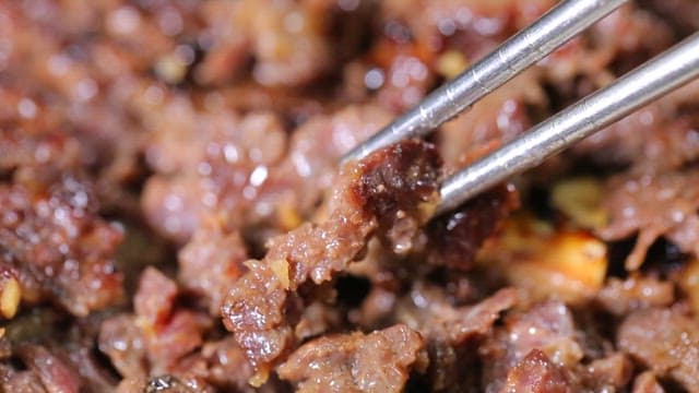 Grilled beef being picked up with chopsticks