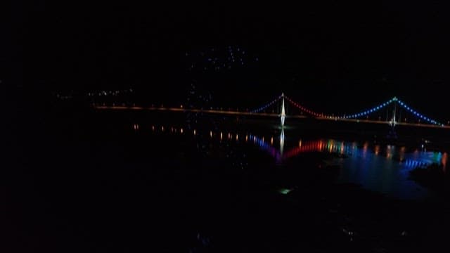 Illuminated bridge and drone light show at night