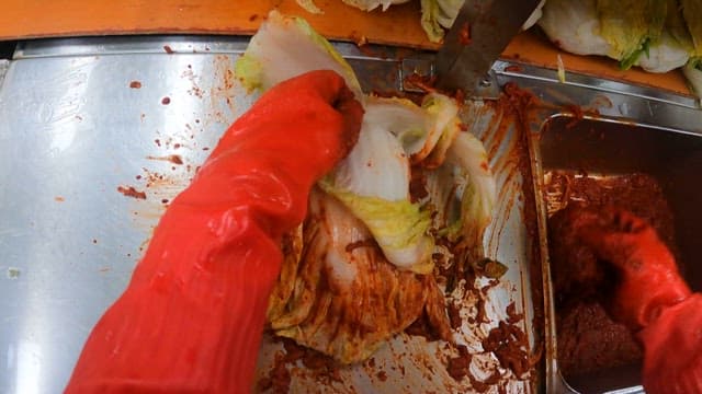 Worker making kimchi from cabbage at a food factory