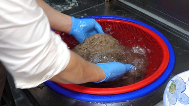 Washing buckwheat noodles in cold water in a restaurant kitchen