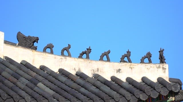 Ornate tiled roof with dragon sculptures against a clear blue sky