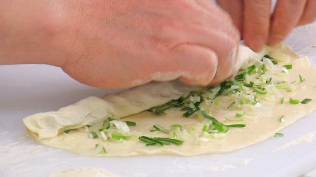 Rolling dough with green onions inside