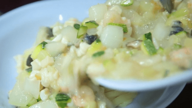 Pouring the jjajang sauce mixed with seafood and vegetables into a bowl of noodles