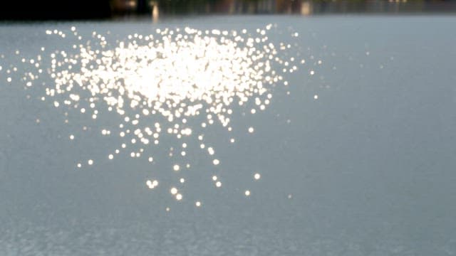 Sunlight reflecting and sparkling on calm water surface