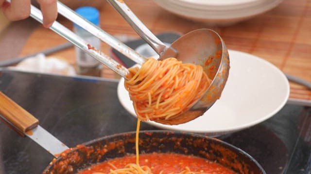 Serving pasta with red bell pepper sauce on a plate