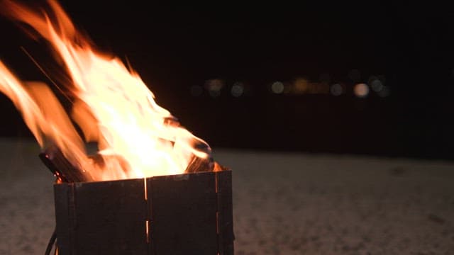 Flames dancing in a metal fire pit at night