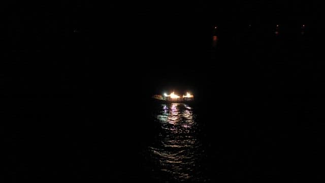 Illuminated boat on a dark night sea