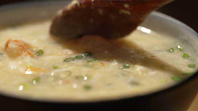 Bowl of warm crab meat porridge with plenty of vegetables and seafood