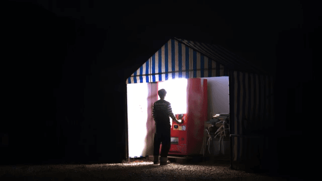 Person using a vending machine in a tent at night