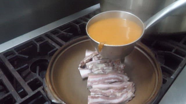 Pouring Broth over Vegetables and Meat in a Pot