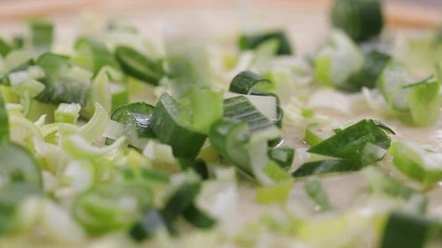 Scallions being spread on flour dough