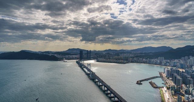 Evening view of the busy port city Busan with a cloudy sky and Gwangan Bridge