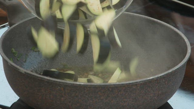 Cooking the trimmed eggplants in a hot pan.