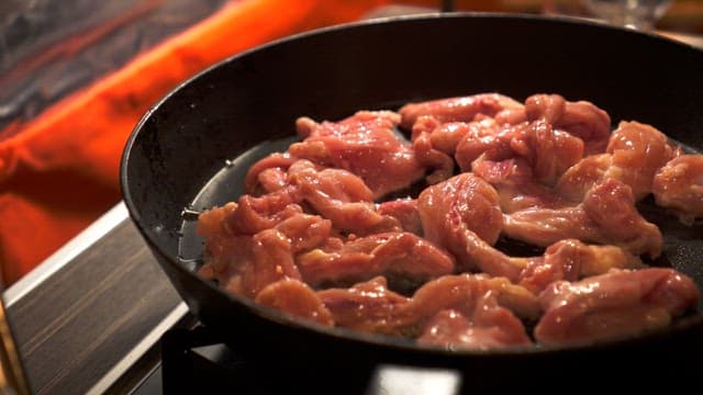 Pepper sprinkled on meat on a hot frying pan with oil