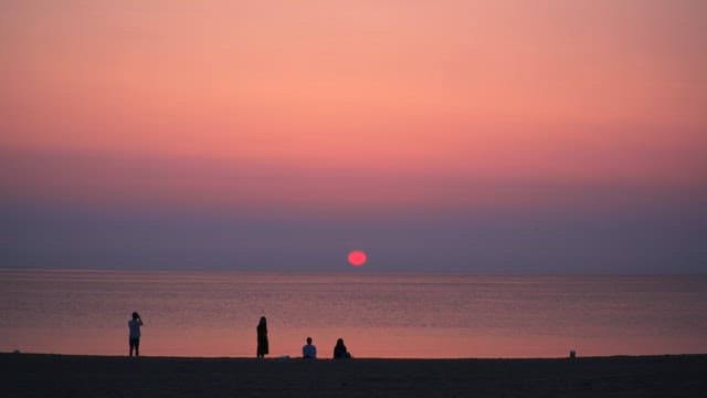 Sunrise over a calm beach with people