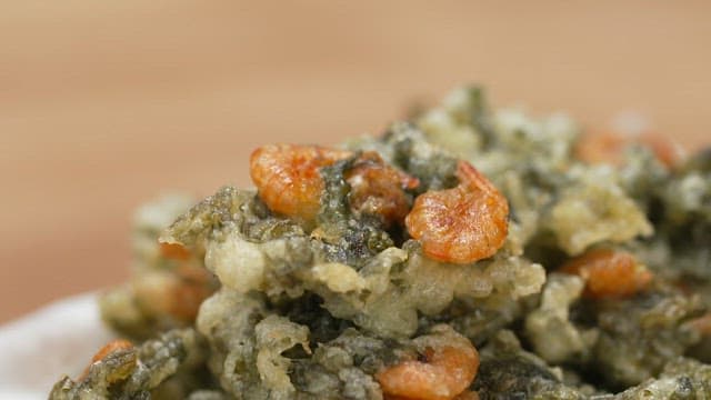 Fork poking into a portion of fried shrimp and laver
