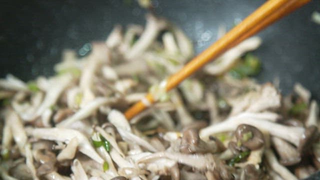 Oyster mushrooms being stir-fried in a pan