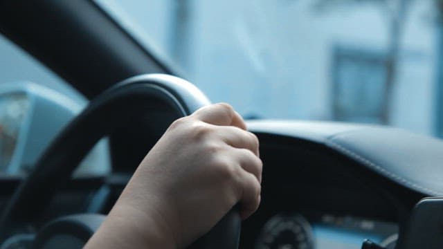 Hand gripping the steering wheel while driving