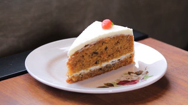Slice of carrot cake on a plate and warm tea